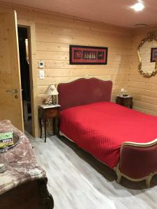 1 dormitorio con cama roja y pared de madera en chalet vosgien, en Le Ménil