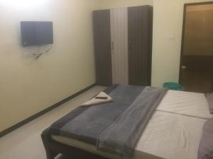 1 dormitorio con 1 cama y TV en la pared en ComfortWings en Coimbatore