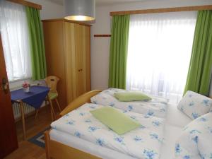a bedroom with two beds and a table and a window at Pension Bayrhammer in Faistenau
