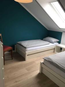 een slaapkamer met 2 bedden en een blauwe muur bij fewo anderswo in der Nähe von Stralsund in Pantelitz +9 foto's