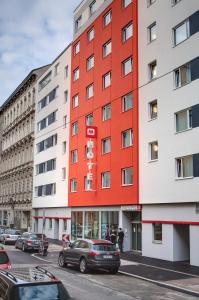 a red building on the side of a street at MEININGER Hotel Wien Downtown Franz in Vienna