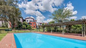 a swimming pool with a pergola next to a building at JoziStay @ Jackal Creek Apartments in Roodepoort