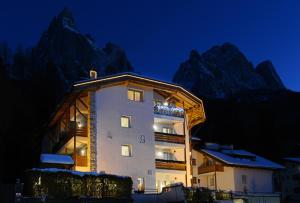 a building in front of a mountain at night at Alpin-Residence Amadeus in Siusi