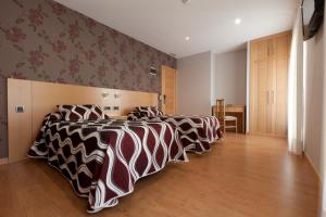 Hostal Jemasaca-Palma61 في مدريد: غرفة نوم بثلاث اسرة شراشف سوداء وبيضاء