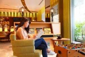 a woman sitting in a chair reading a book at Kyoto Tower Hotel Annex in Kyoto