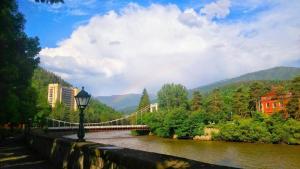 a bridge over a river with a rainbow at Our house in Borjomi