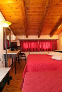 a bedroom with a red bed and a desk at Hotel Varonos in Delphi