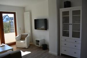 a living room with a tv and a white cabinet at Huus Parlbuggt in Büsum