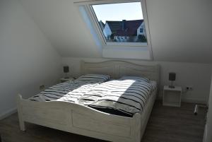 Bett in einem weißen Zimmer mit Fenster in der Unterkunft Huus Parlbuggt in Büsum