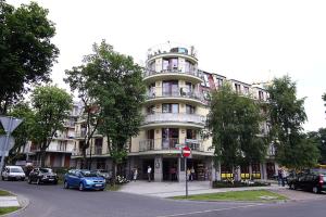 a large white building with cars parked in front of it at Apartamenty Świnoujście - Róża Wiatrów in Świnoujście