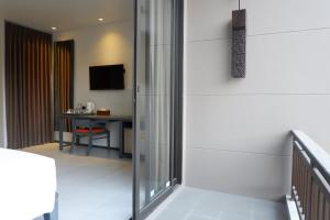 a room with a sliding glass door with a desk at Maehaad Bay Resort - SHA Plus in Mae Haad