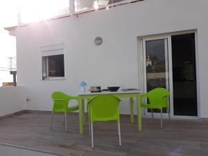 a dining room with a table and green chairs at modern holiday apartment with private pool in Adeje