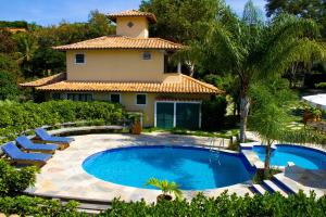 a swimming pool in front of a house at Residence dos Búzios in Búzios