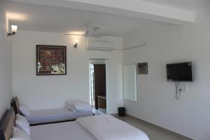 a bedroom with two beds and a flat screen tv at Little Rann Resort in Zainābād