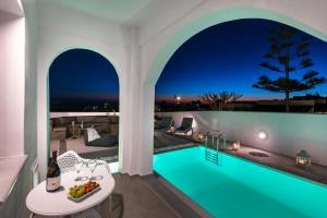 a villa with a swimming pool at night at White Harmony Suites in Megalochori