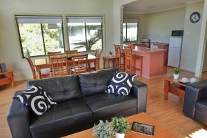 a living room with a black leather couch and a kitchen at SkyView Villa in Kangaroo Valley