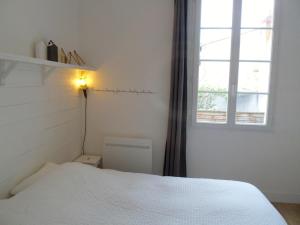 1 dormitorio con cama blanca y ventana en L' Appart du Marché, en La Rochelle