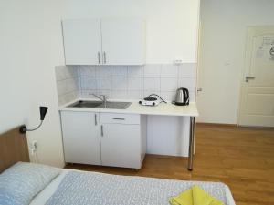 a kitchen with white cabinets and a sink and a bed at Capital Guesthouse Budapest in Budapest