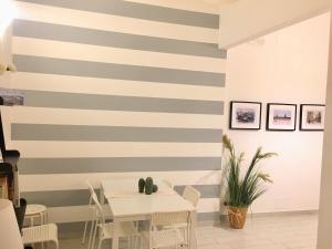 eine gestreifte Wand in einem Esszimmer mit einem weißen Tisch in der Unterkunft Torrearsa 17 in Trapani