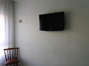 TV de pantalla plana colgada en una pared blanca en Hotel Avenida, en Gijón