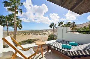 a balcony with a bed and chairs and a view of the beach at INNSiDE by Meliá Fuerteventura – Adults Only in Costa Calma