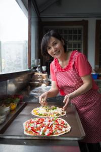 通霄鎮的住宿－如意園 ，一个女人在厨房里准备两份比萨饼