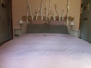 a bedroom with a large bed with white sheets at Au Bois Flotté in Hourtin