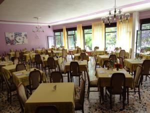 una sala da pranzo con tavoli, sedie e finestre di Hotel Levico a Levico Terme