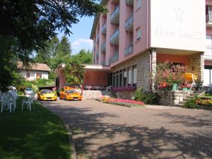 dos coches amarillos estacionados frente a un hotel en Hotel Levico en Levico Terme