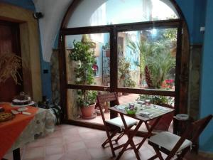 une table et des chaises dans une pièce avec une grande fenêtre dans l'établissement La Finestra sul Cortile B&B, à Sciacca