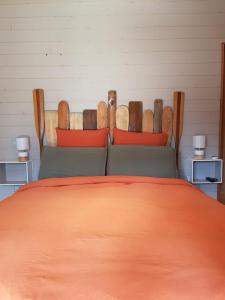 a bedroom with a bed with an orange bedspread at Au Bois Flotté in Hourtin