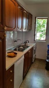 eine Küche mit Holzschränken, einem Waschbecken und einem Fenster in der Unterkunft Podaca house in Podaca