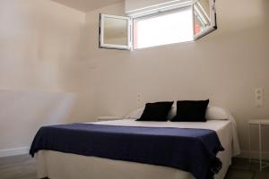 a bedroom with a bed with a blue blanket and a window at Aparportu in Mundaka