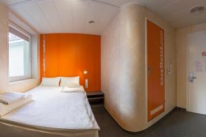 a bed in a room with an orange wall at easyHotel Budapest Oktogon in Budapest
