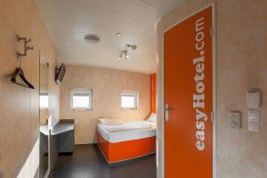 a bathroom with a bed, a toilet, and a window at easyHotel Budapest Oktogon in Budapest