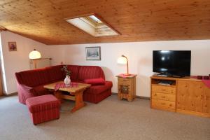 - un salon avec un canapé rouge et une télévision dans l'établissement Landhaus Schmid Schönau, à Schönau am Königssee