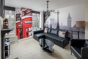 Skyline Serviced Apartments - London Bridge في لندن: غرفة معيشة مع أريكة سوداء وكشك هاتف احمر