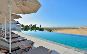 a swimming pool with chairs and an umbrella at INNSiDE by Meliá Fuerteventura – Adults Only in Costa Calma