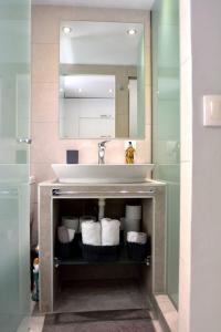 een badkamer met een wastafel, een spiegel en handdoeken bij Liston Apartment in Corfu-stad