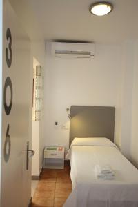 1 dormitorio con 1 cama con colcha blanca en Hostal Ripoll Ibiza, en Ibiza