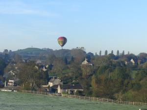 a hot air balloon is flying over a village at Whidlecombe Farm in Priston