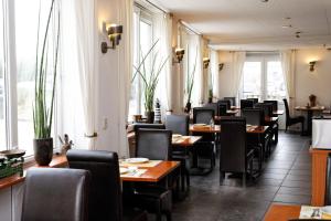 a dining room with tables and chairs and windows at Hotel Noordzee in Domburg