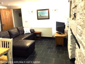 Una sala de estar con un sofá de cuero negro y un televisor. en Museum Apartment, en Looe