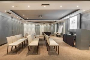 a conference room with tables and chairs and a screen at The Excelsior - Small Luxury Hotels of the World in Thessaloniki