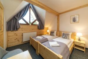 two twin beds in a room with a window at Villa Kaplowa Chata & SPA in Zakopane