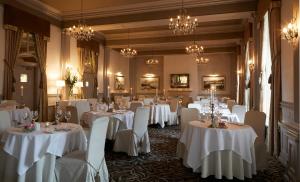スカーバラにあるPalm Court Hotelの白いテーブルと椅子、シャンデリアが備わる宴会場