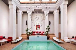 a lobby with a pool and a chandelier at Hotel & Spa Riad Al Jazira in Marrakech