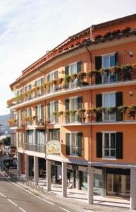 ein großes orangefarbenes Gebäude mit Balkonen und Pflanzen darauf in der Unterkunft Hotel Residence Dei Fiori in Baveno