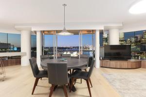 uma sala de jantar com uma mesa e cadeiras e uma televisão em 3 Bedroom Darling Harbour Apartment em Sydney