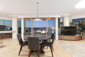 a dining room with a table and chairs and a television at 3 Bedroom Darling Harbour Apartment in Sydney